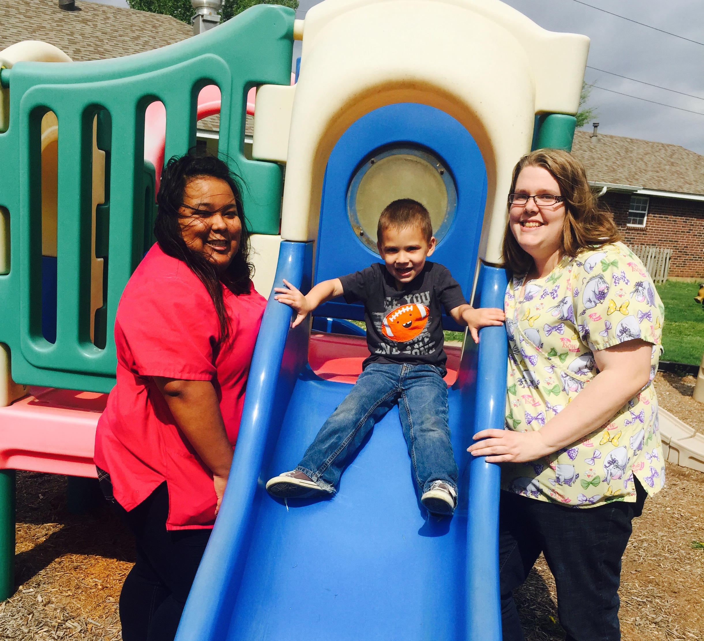 A picture of a boy and teachers on a playground